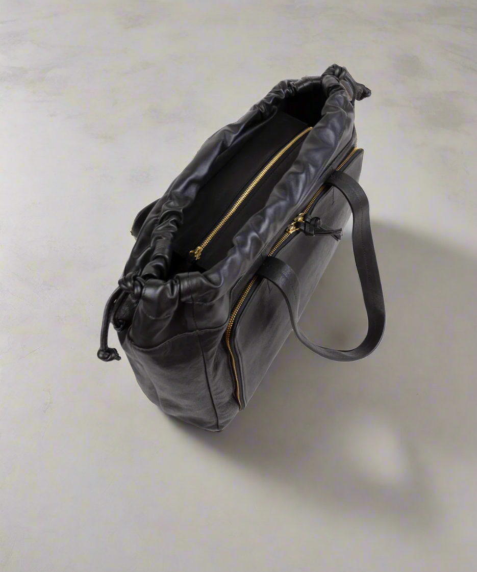 Black handbag with gold zipper on a light gray background