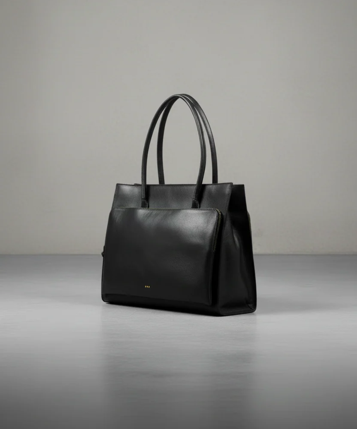 Black leather tote bag on a gray background