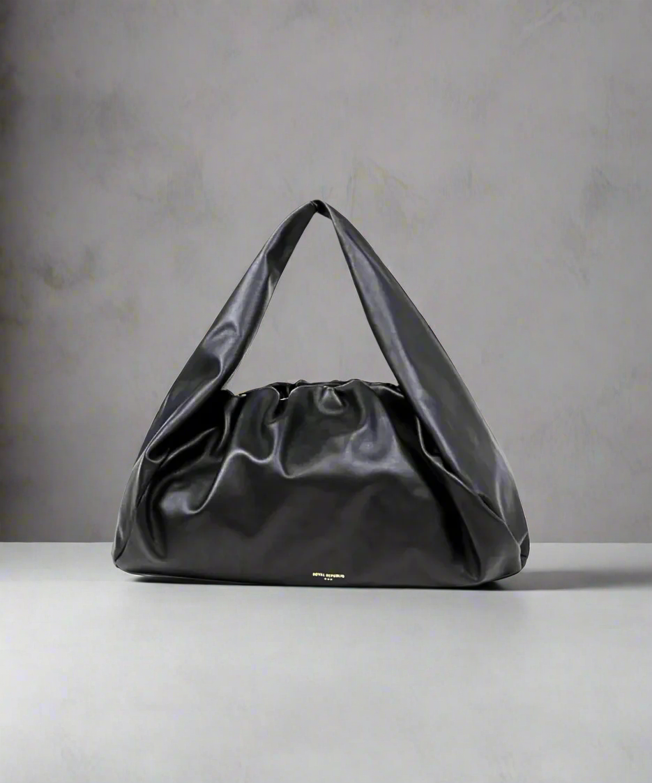 Black Royal RepubliQ Oversized Pouch handbag on a gray surface with a neutral background