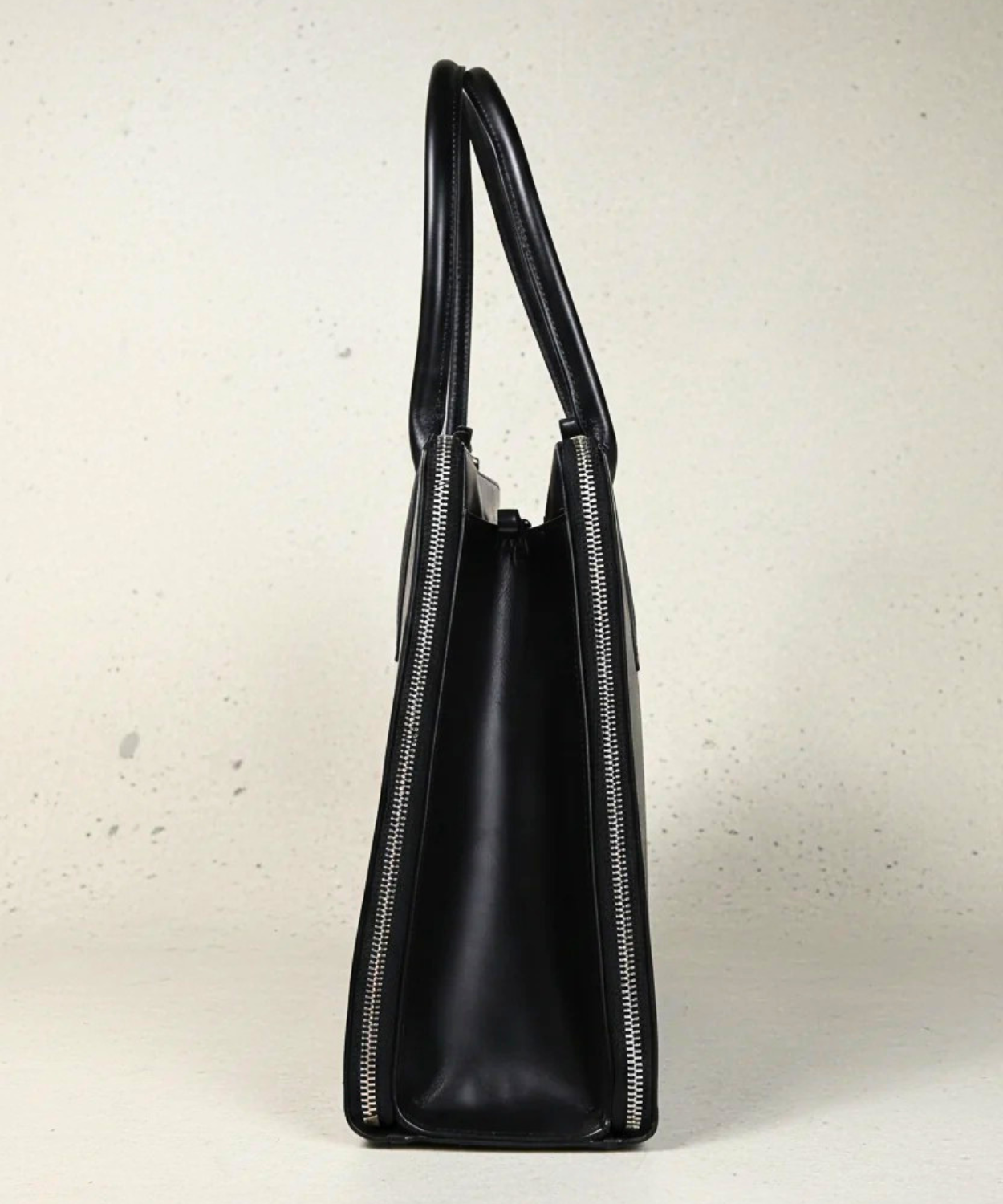 Black handbag with a zipper on a light gray background