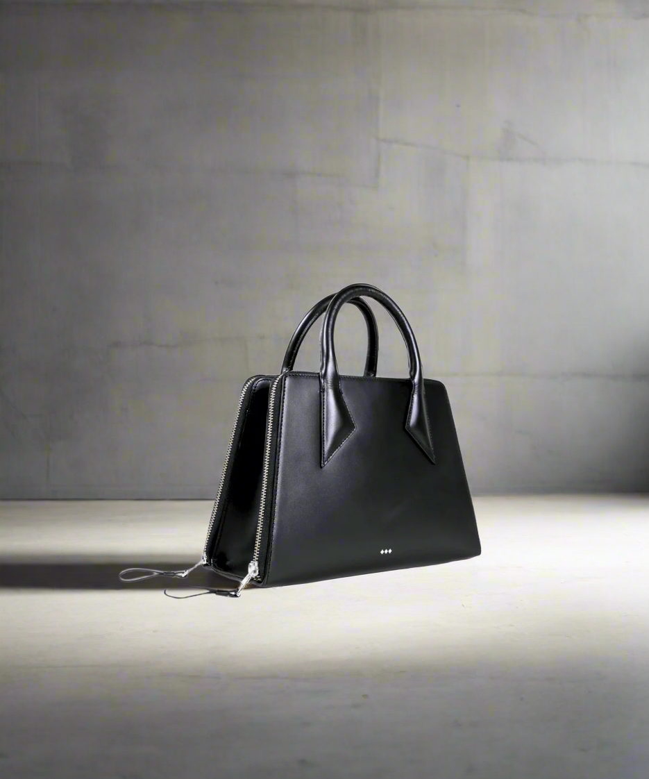 Black handbag on a gray surface with a neutral background
