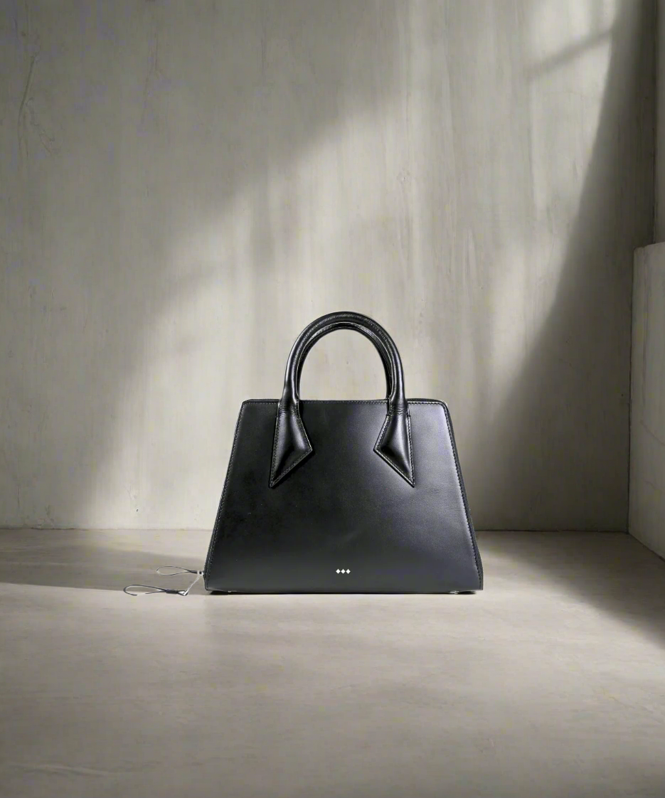 Black handbag on a light gray surface with a neutral background
