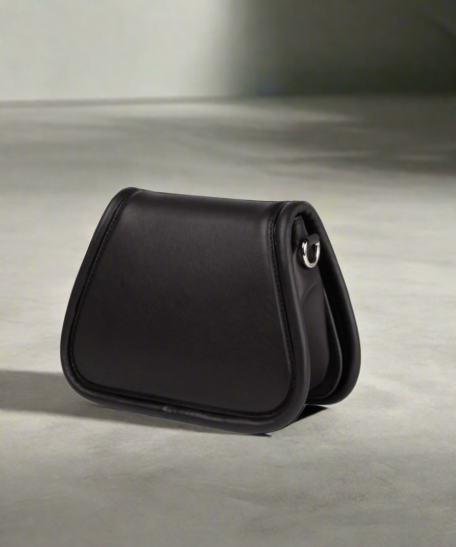 Black leather saddle bag on a gray background