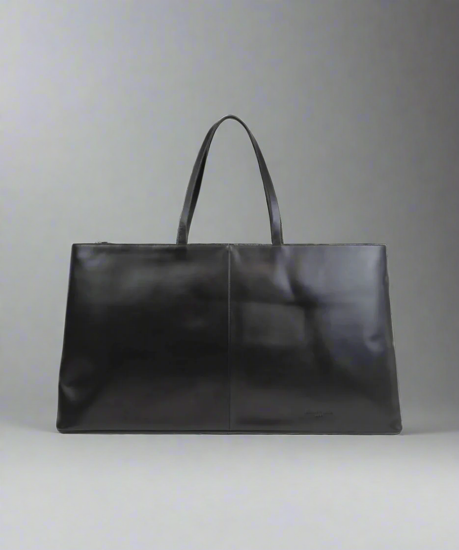 Black leather tote bag on a gray background