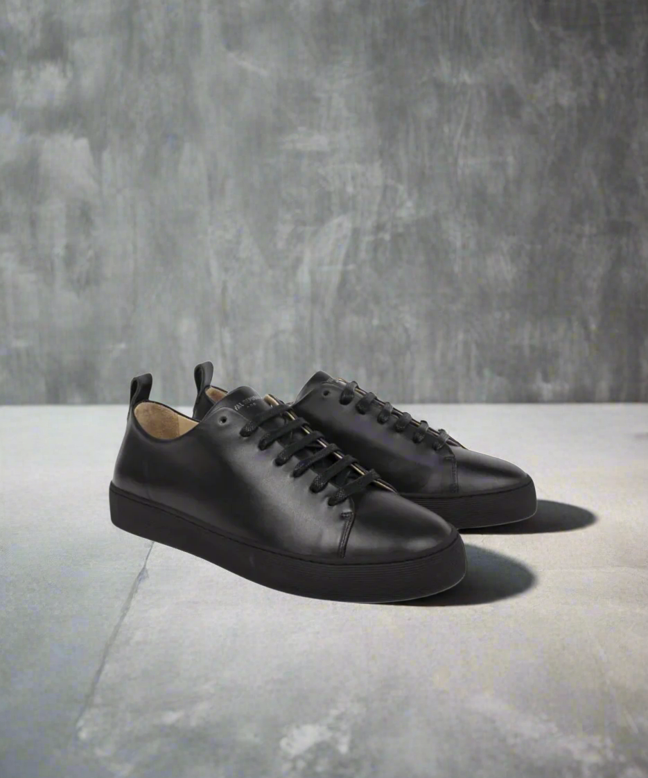 Pair of black leather sneakers on a grey background