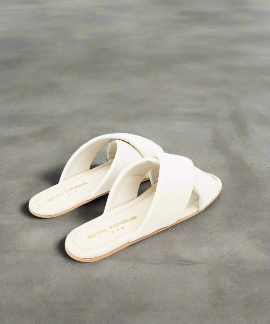 White sandals with 'Saks Fifth Avenue' branding on grey background