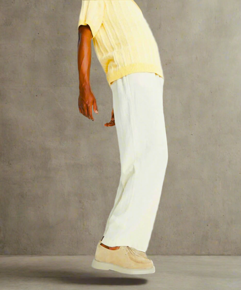 Person wearing a yellow top and white pants on a gray background
