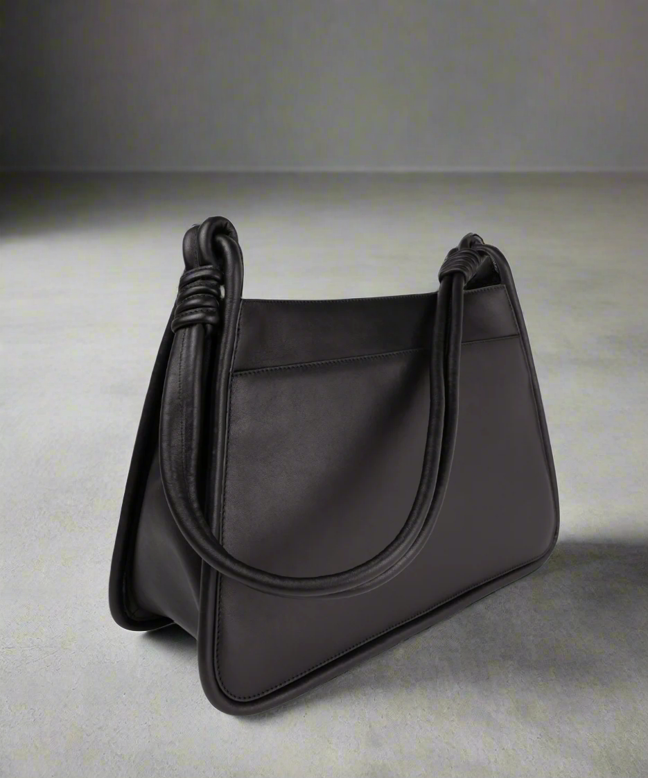 Black handbag with knotted handles on a gray background