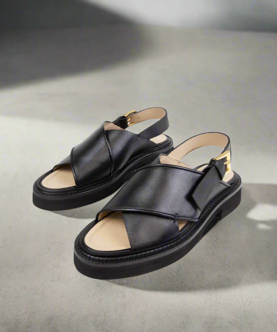 Black sandals with beige soles on a gray background