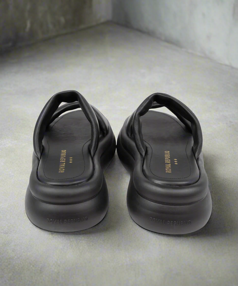 Pair of black sandals with brand name on a gray background