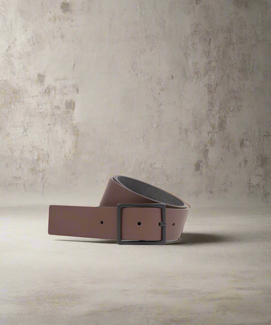 A brown leather belt with a thin metal buckle, displayed on a plain background.