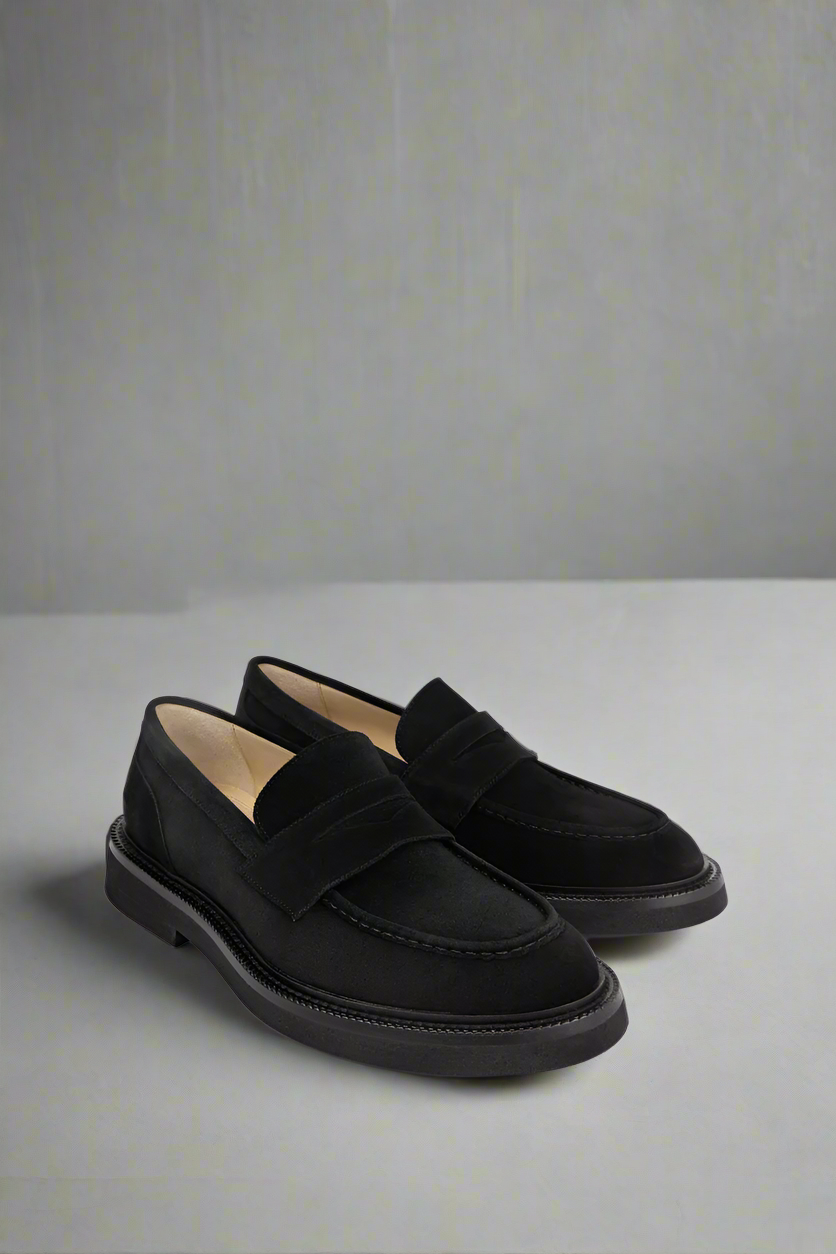 Pair of black Royal RepubliQ loafers on a light gray background