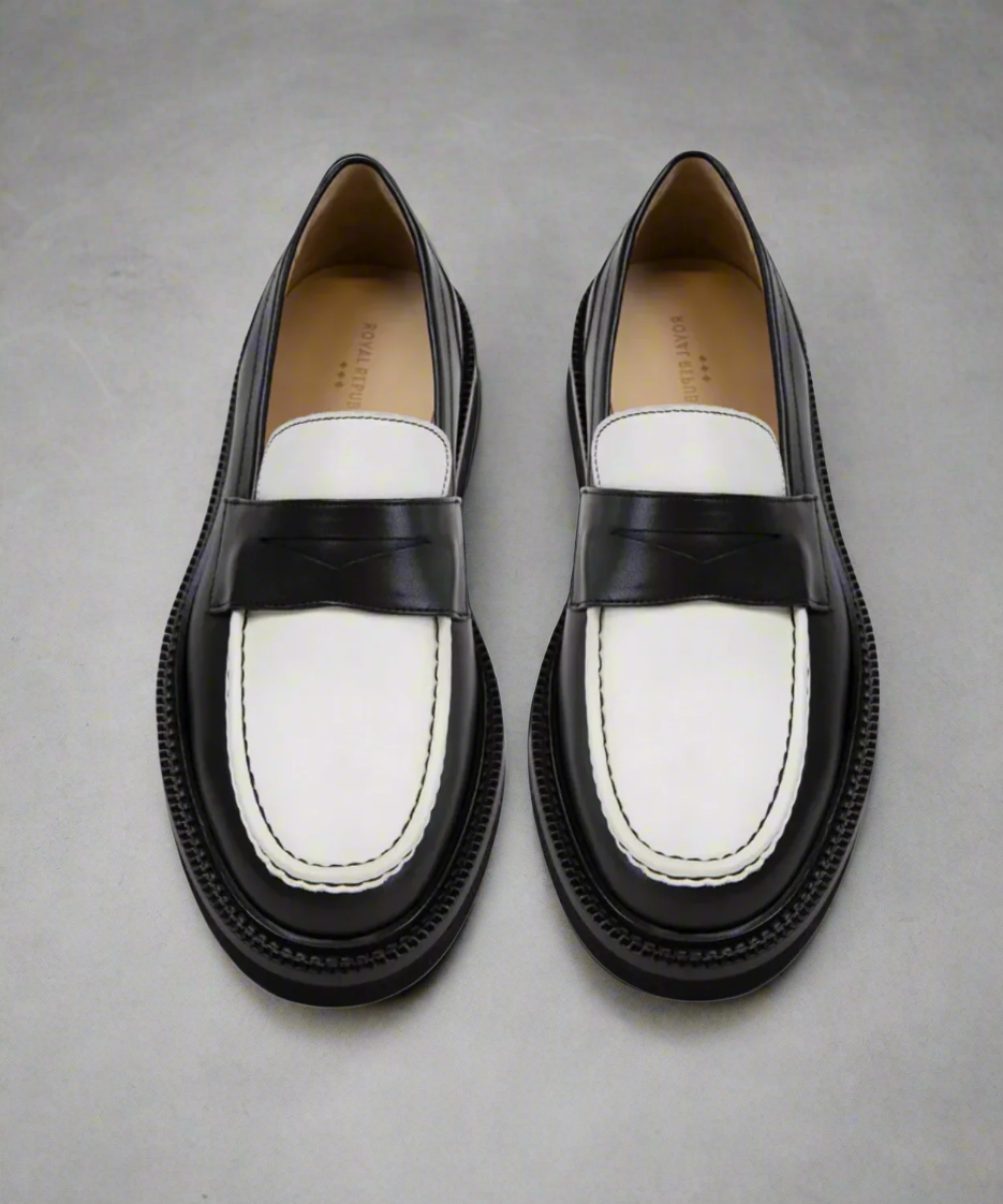 Pair of Royal RepubliQ black and white loafers on a gray background