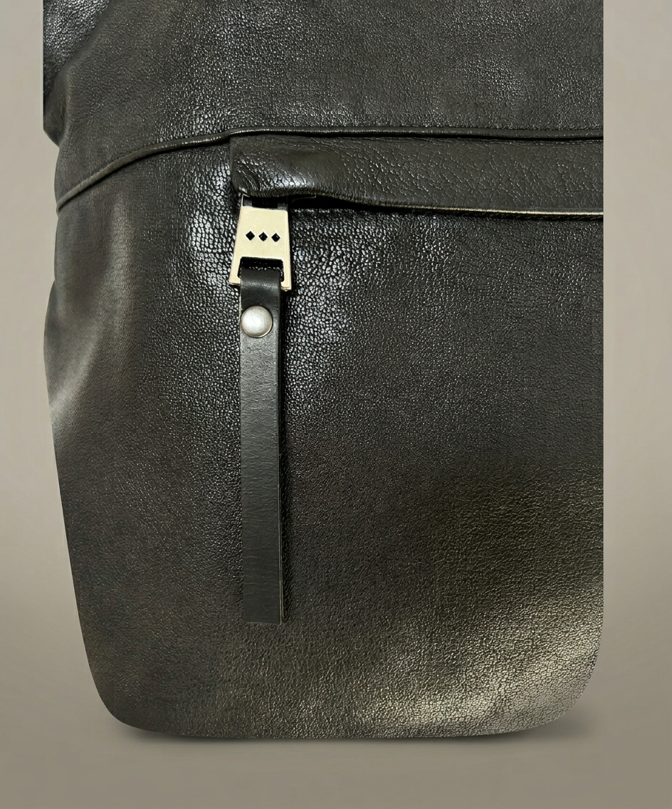 Black leather bag with a strap and buckle on a beige background