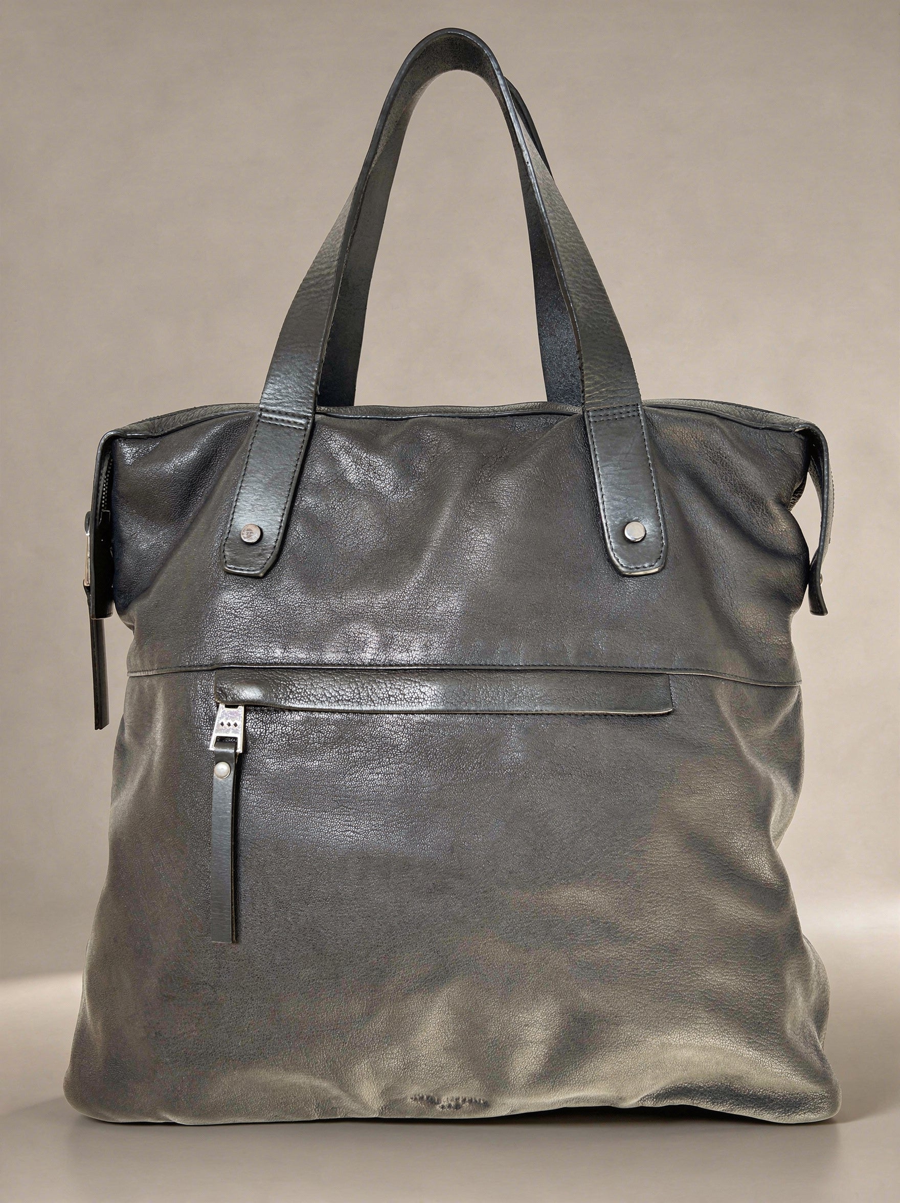 Black leather tote bag on a beige background