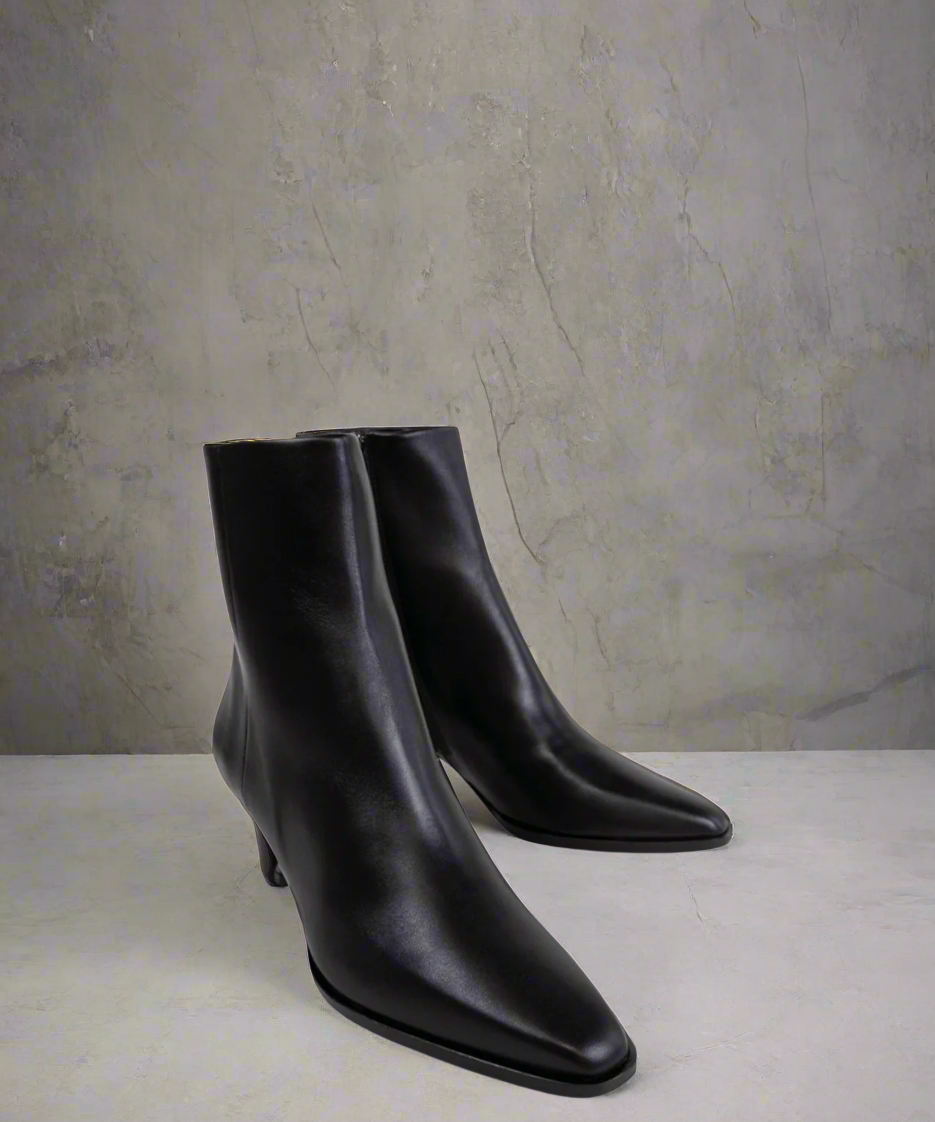 Pair of black ankle boots on a light gray background