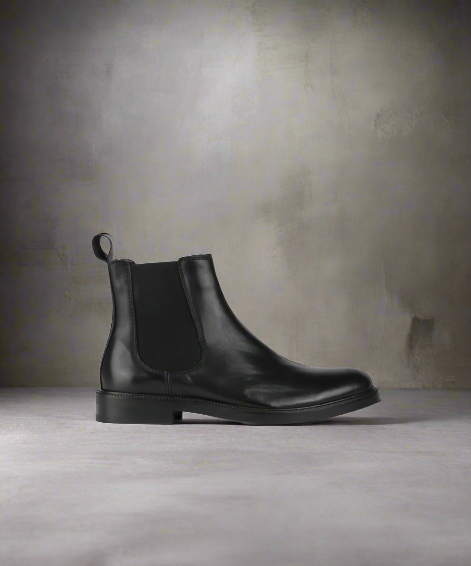 A black Chelsea boot with a smooth leather finish, a low heel, and a pull tab on the side.