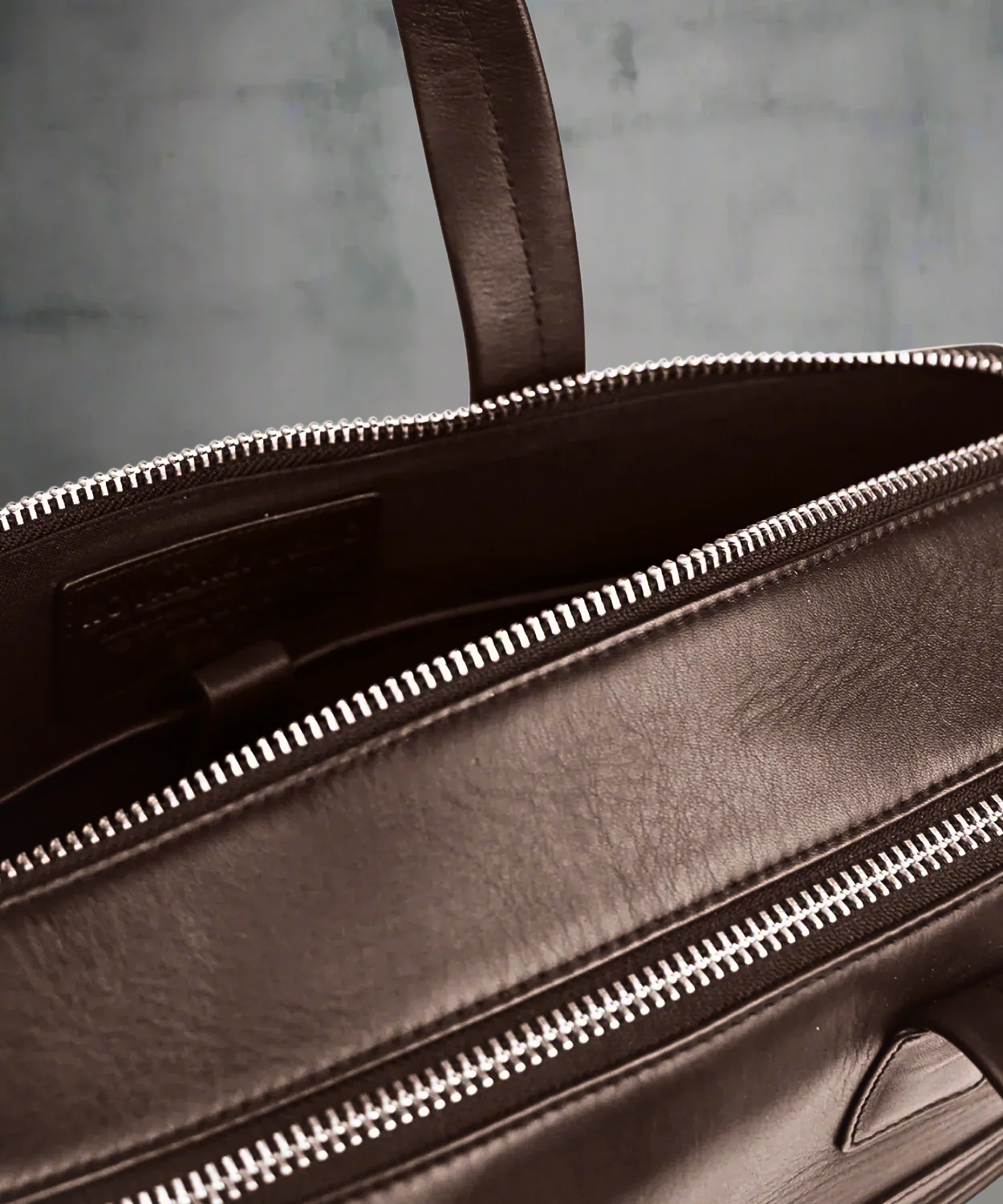 Brown Royal RepubliQ leather briefcase with zipper on a gray background