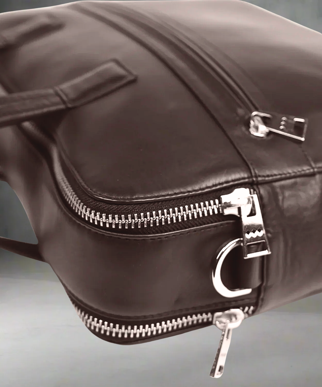Brown Royal RepubliQ leather bag with silver zippers on a gray background