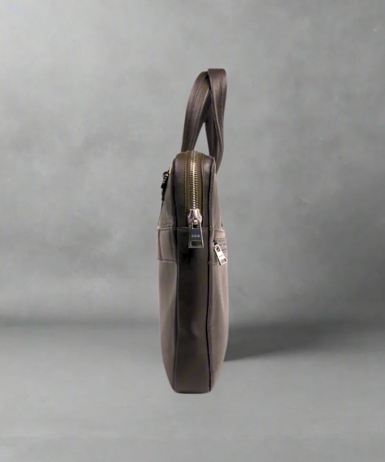 Brown Royal RepubliQ leather bag with a shoulder strap on a gray background