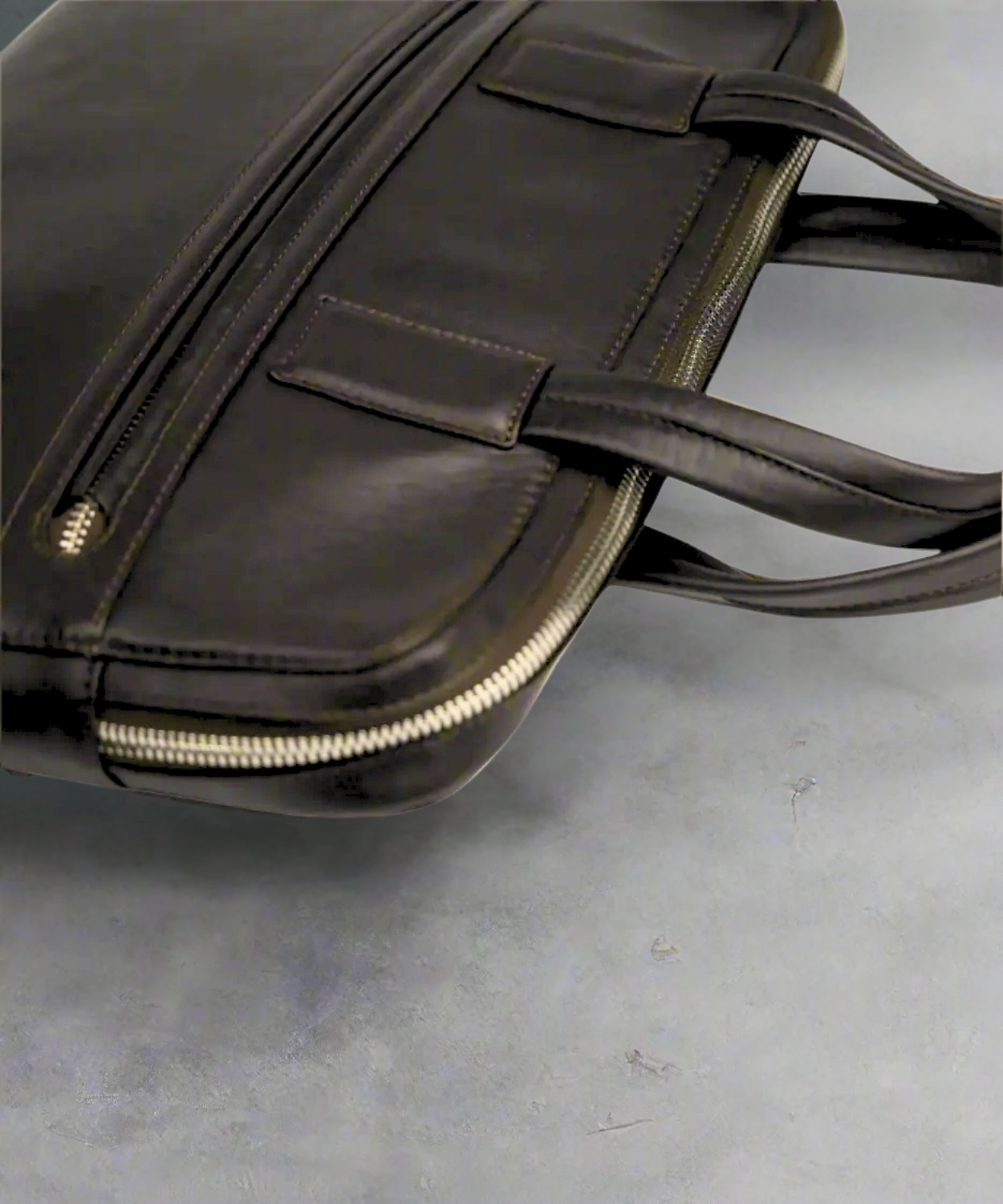 Dark brown Royal RepubliQ leather briefcase on a gray surface