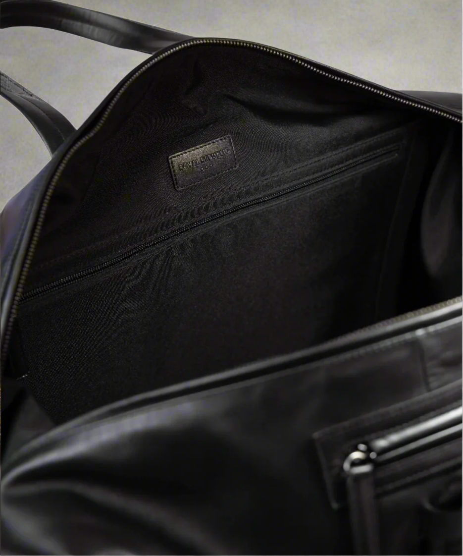 Close-up of a black Royal RepubliQ leather bag with a visible brand label on a white background