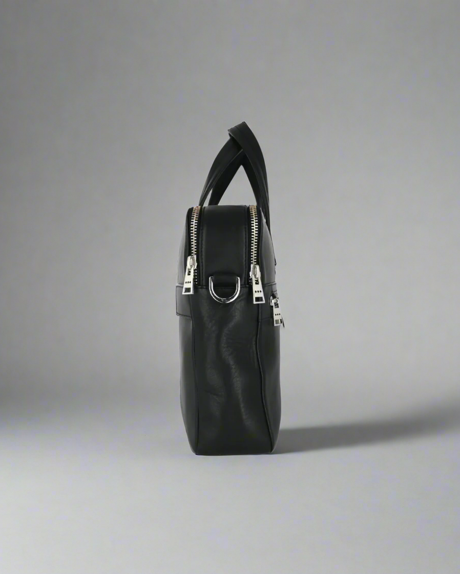 Black Royal RepubliQ leather handbag with silver zippers on a gray background