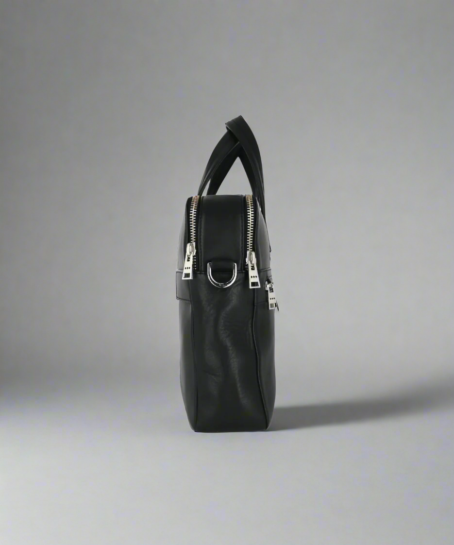 Black Royal RepubliQ leather handbag with silver zippers on a gray background