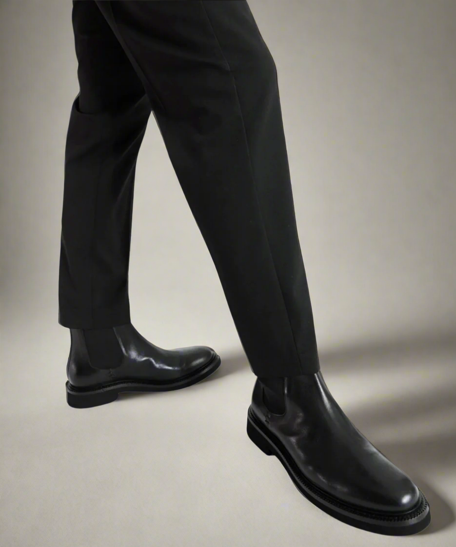 Black leather shoes and pants on a neutral background