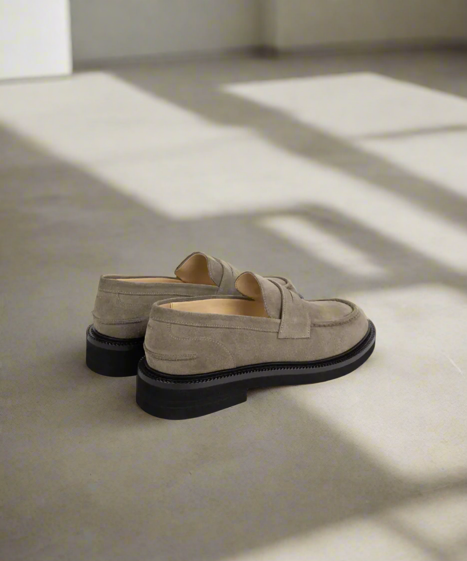 Pair of beige Royal RepubliQ loafers with black soles on a light gray background