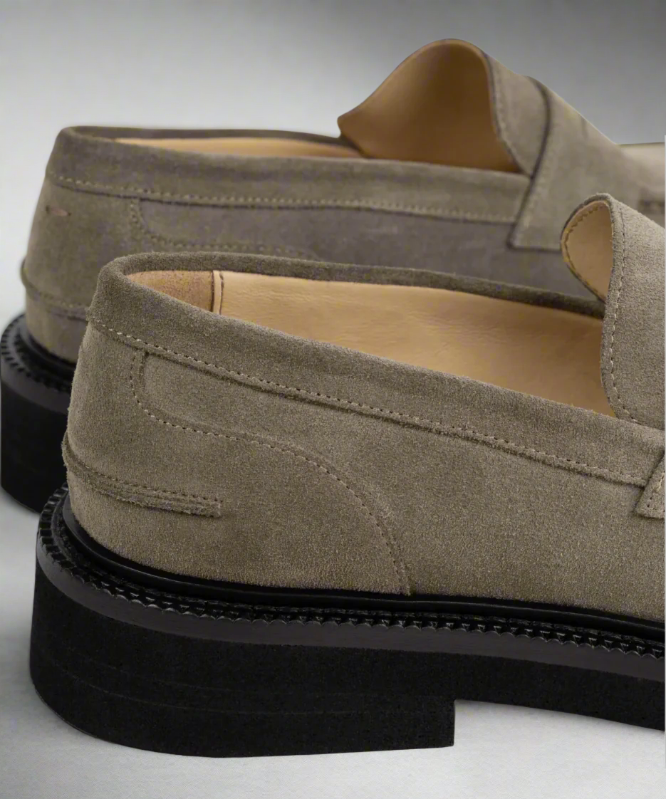 Pair of beige Royal RepubliQ suede loafers with black soles on a light gray background
