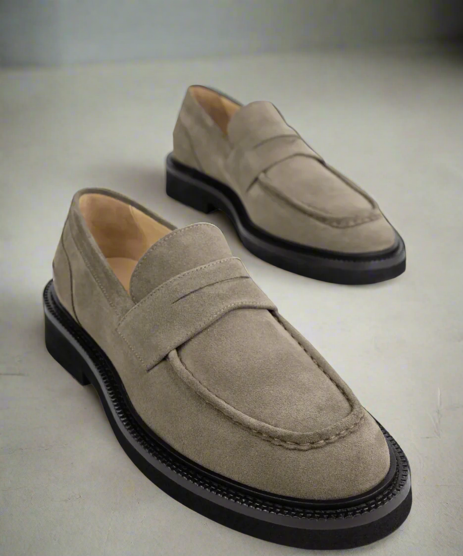 Pair of beige Royal RepubliQ loafers with black soles on a light background