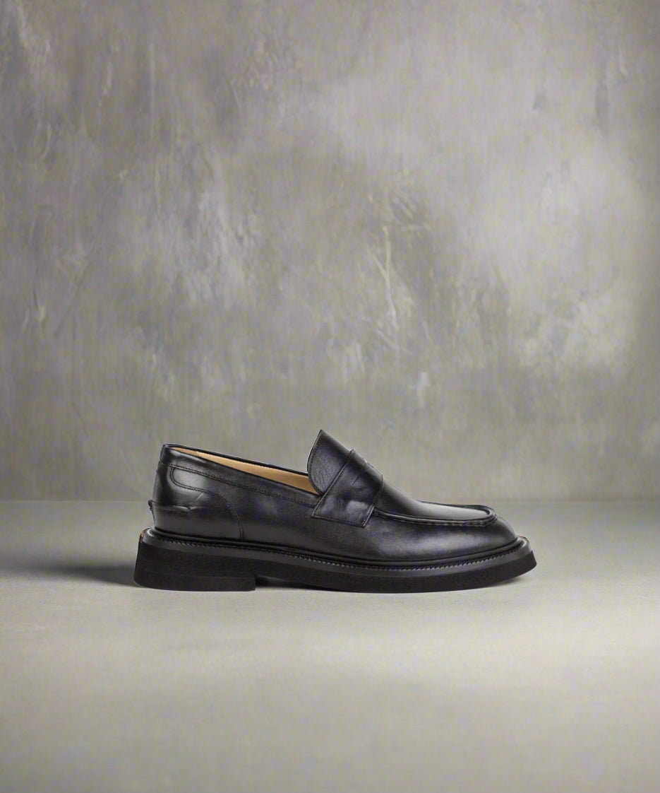 Black loafer shoe on a gray background