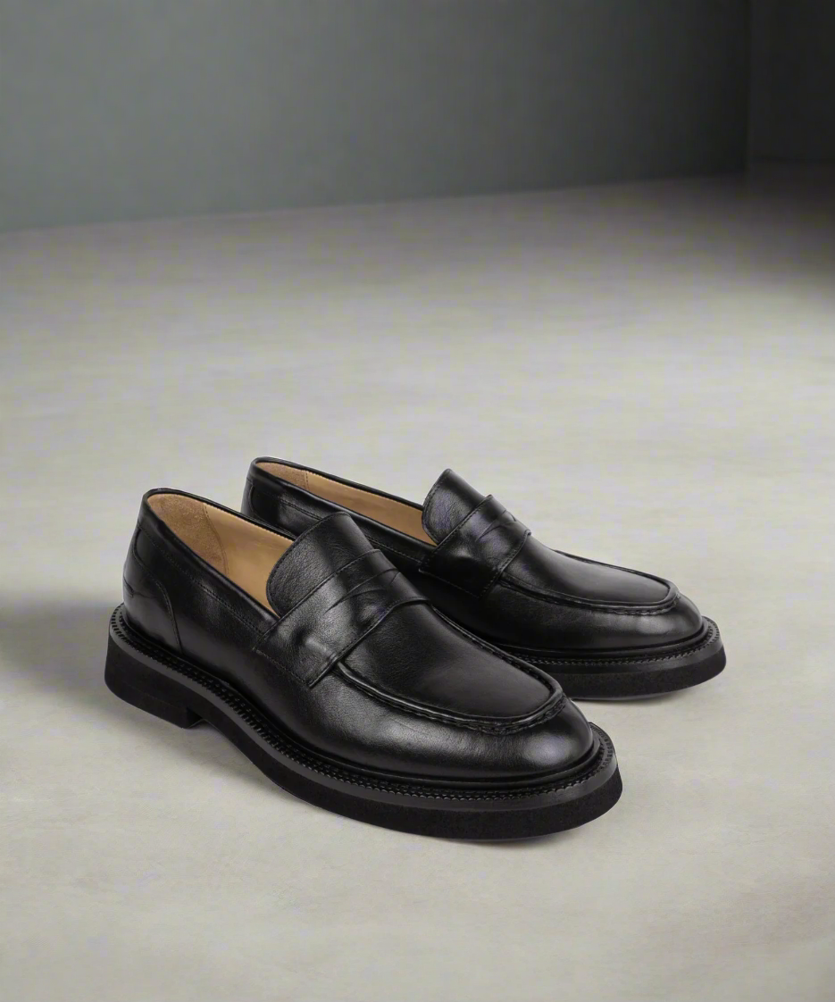 Pair of black leather loafers on a white background
