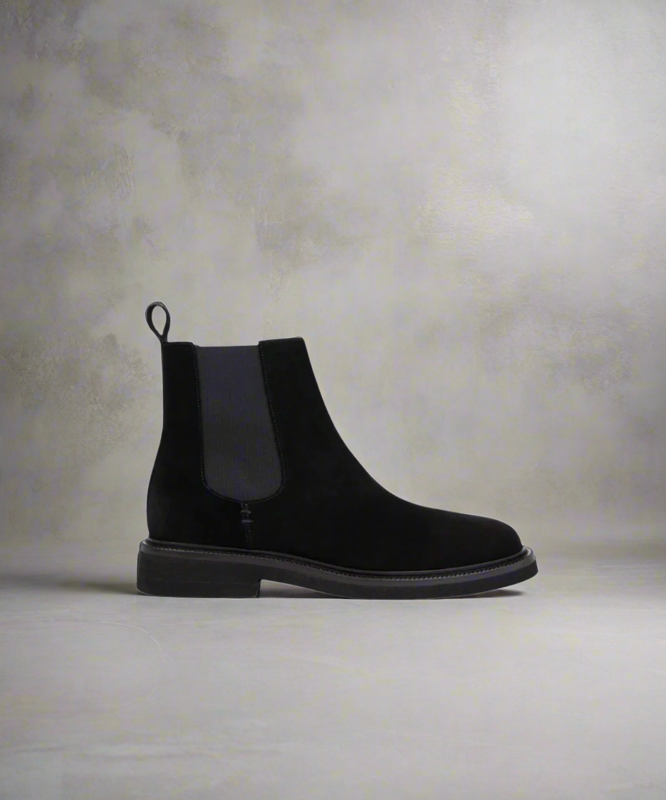 Black Chelsea boot on a textured gray background