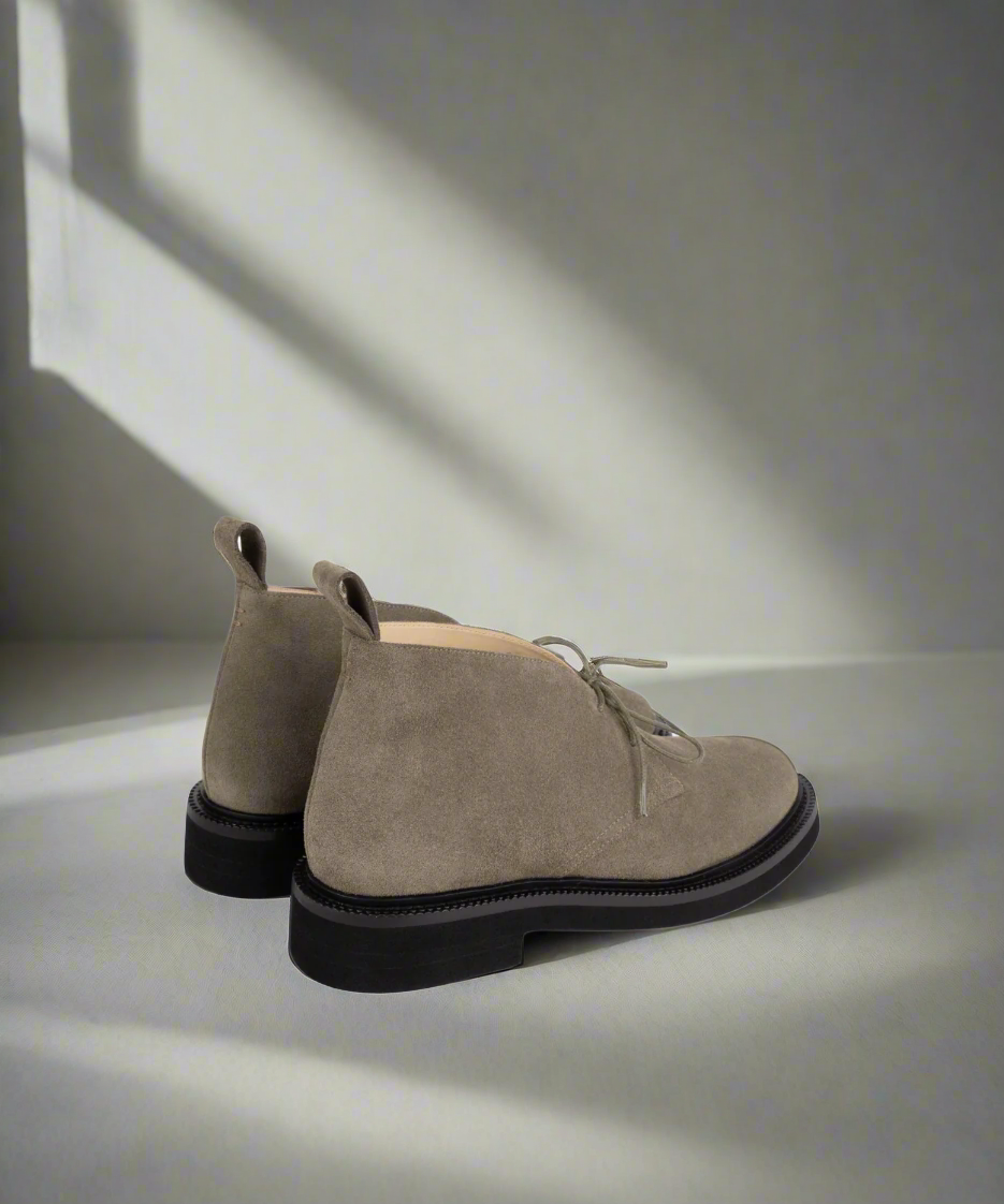 Pair of beige Royal RepubliQ suede shoes with black soles on a light surface with soft shadows.