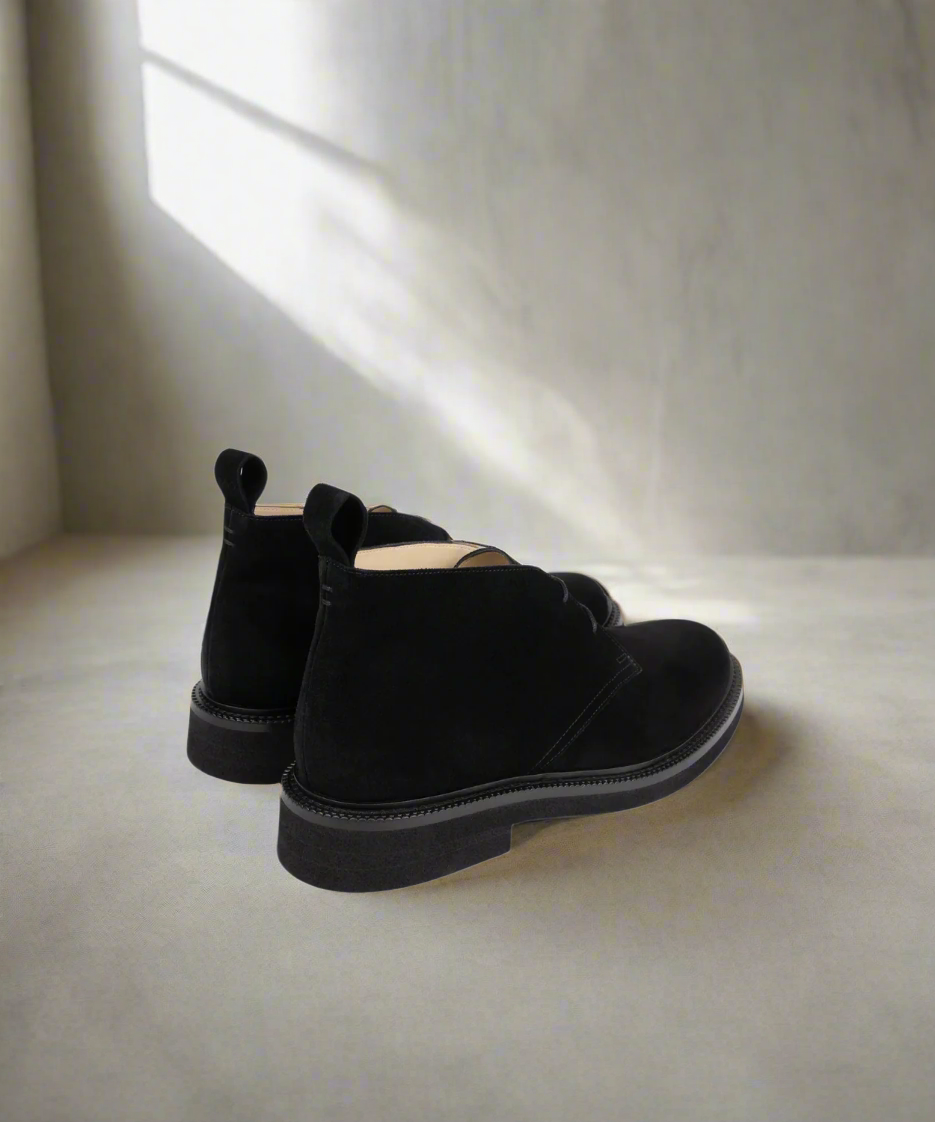 Pair of black boots on a light surface with a soft shadow