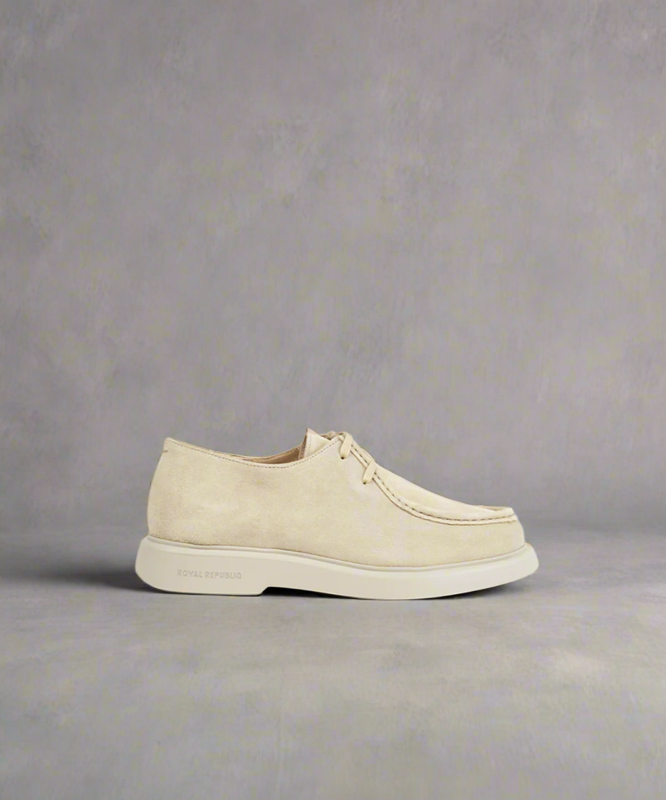 A beige Royal RepubliQ Suede Chukka boot with a modern minimalist aesthetic, featuring a streamlined silhouette and minimal detailing.