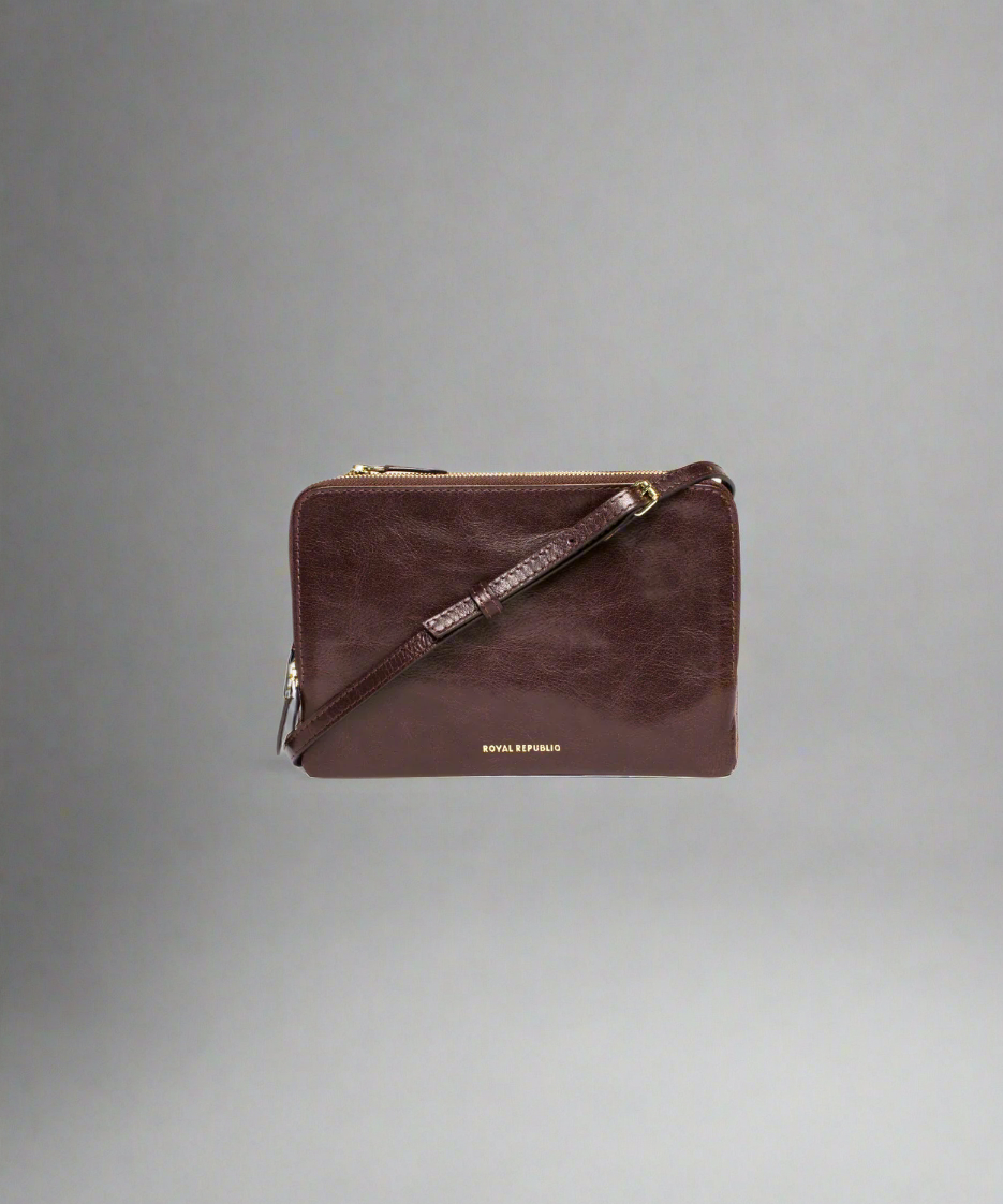 Brown Royal RepubliQ leather clutch bag with a strap on a gray background