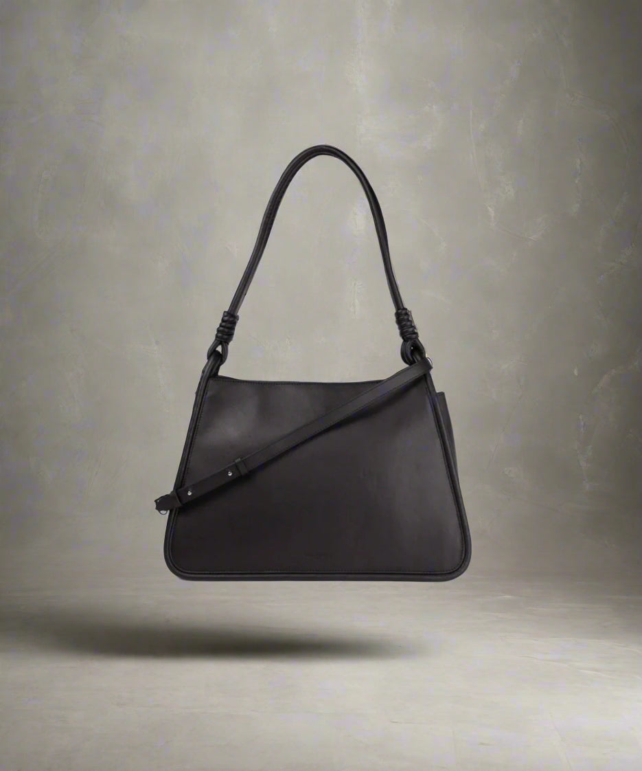 A black leather shopper bag with a shoulder strap and a handle, displayed against a plain background.