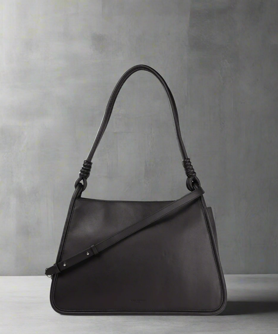 A black Royal RepubliQ leather shopper bag with a shoulder strap and a handle, displayed against a gray background.