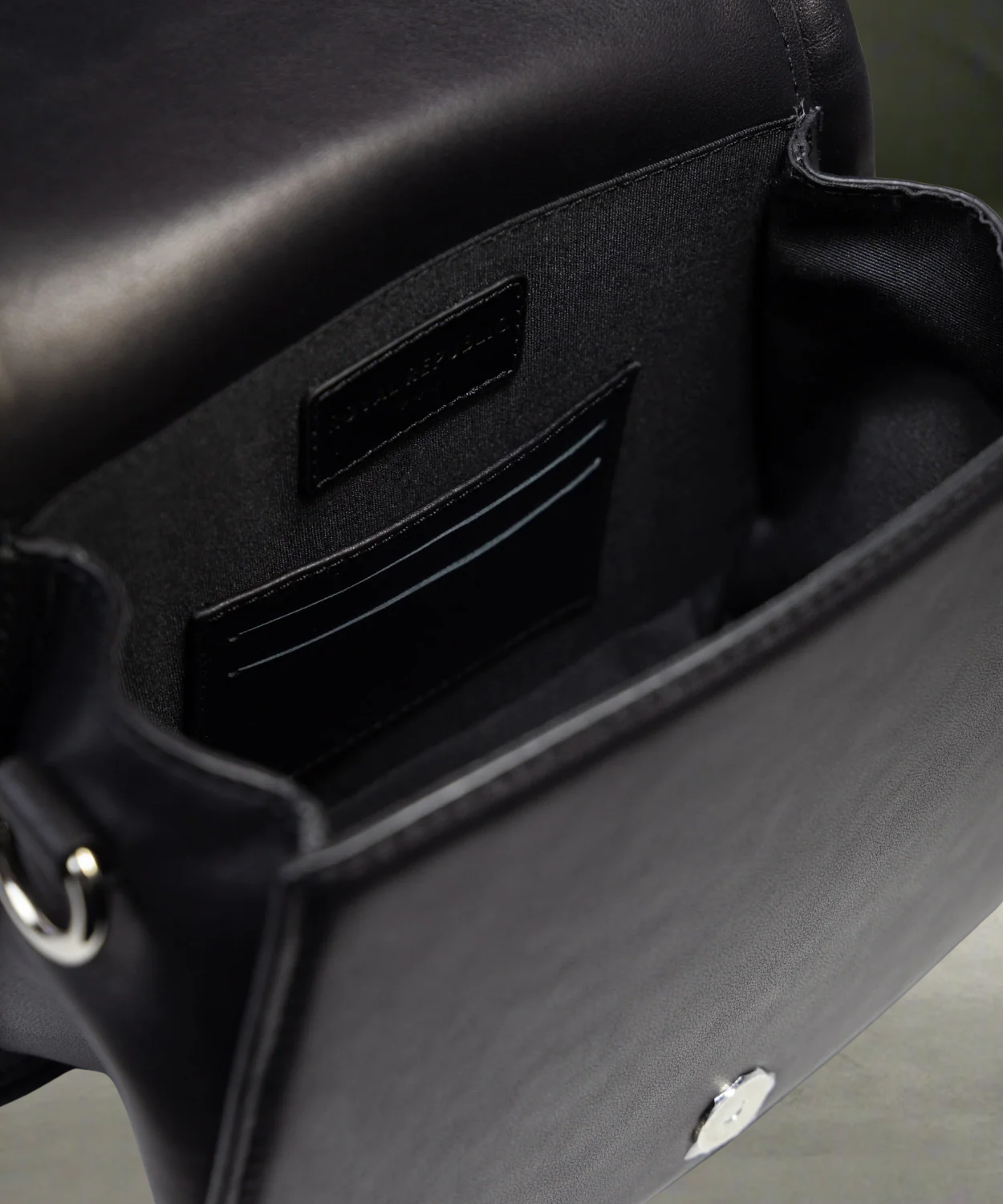 Close-up of a black Royal RepubliQ leather handbag with visible brand name on a neutral background