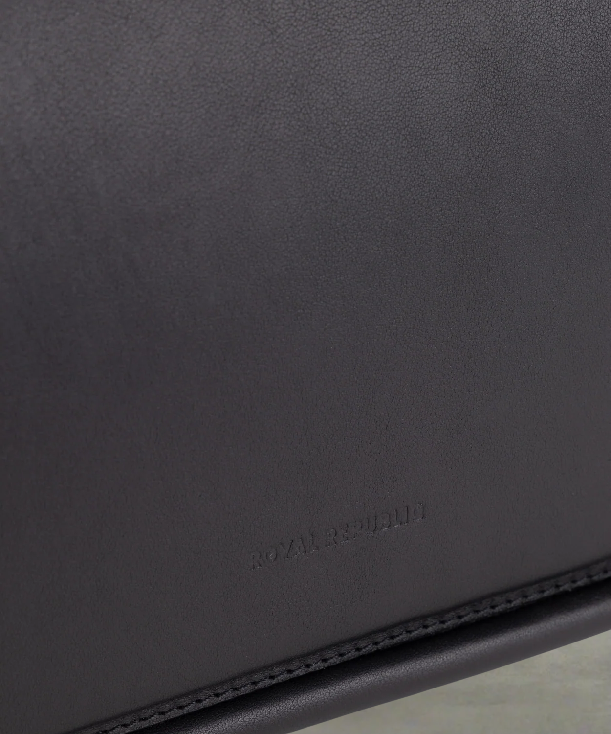 Close-up of a black Royal RepubliQ leather evening bag with 'Royal RepubliQ' embossed branding.