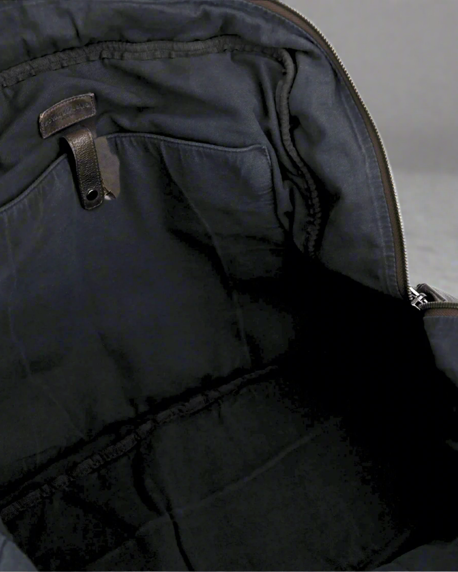Inside close-up of a brown Royal RepubliQ  washed leather weekend bag with zippers on a gray background