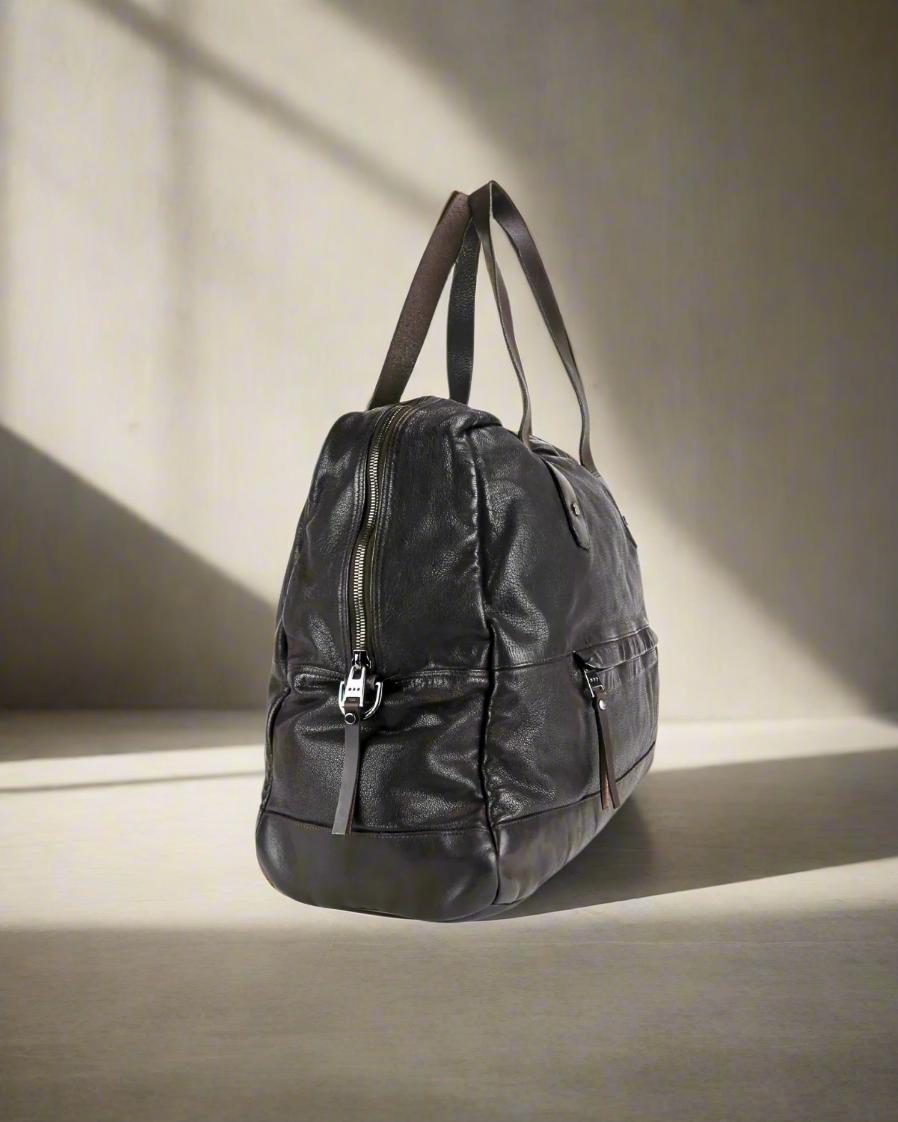 Dark brown Royal RepublQ washed leather weekend bag on a neutral background