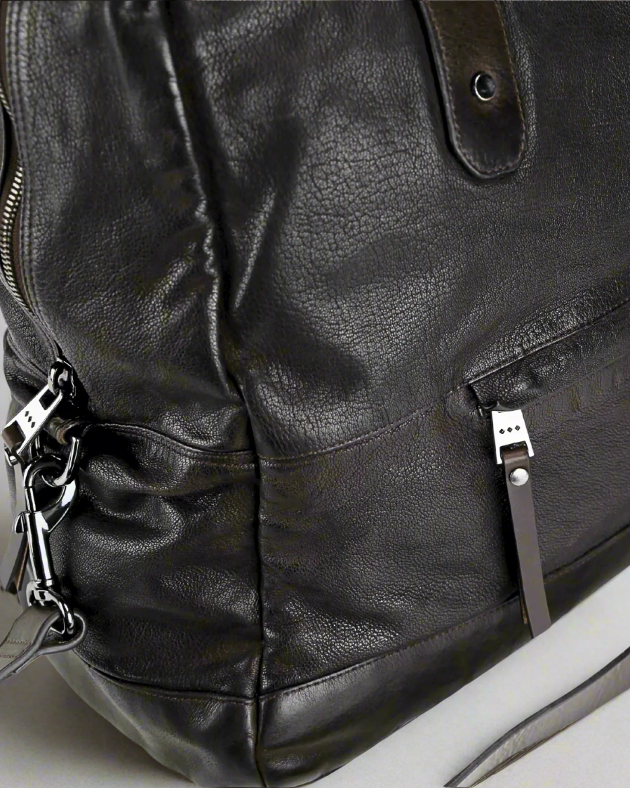 Close-up of a Dark brown Royal RepubliQ washed leather weekend bag with zippers and a strap.