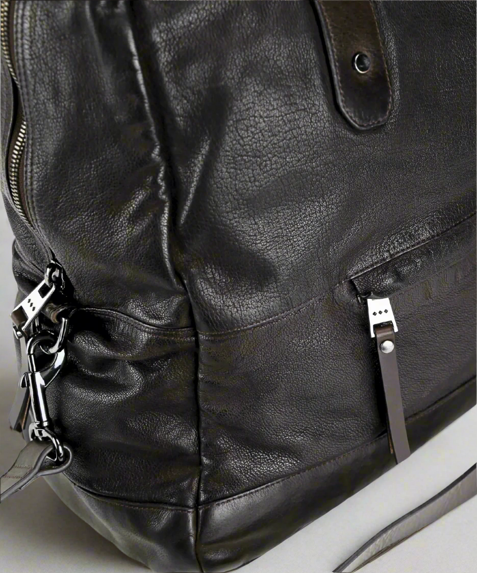 Close-up of a Dark brown Royal RepubliQ washed leather weekend bag with zippers and a strap.