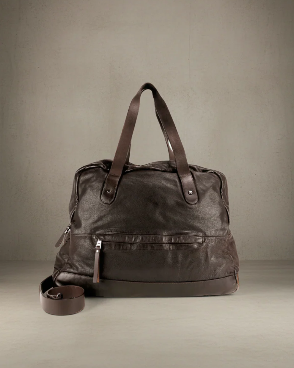 Brown leather duffel bag on a gray background