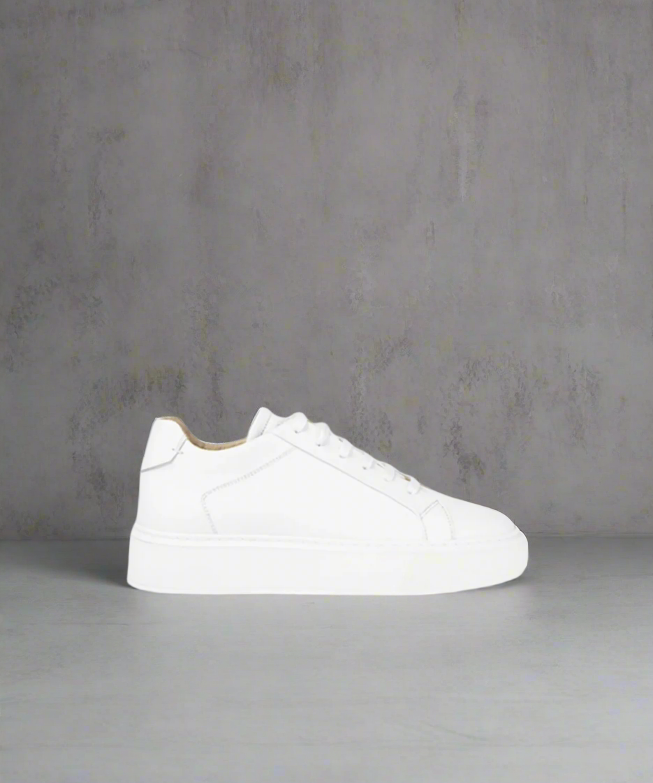 White sneaker on a gray surface with a neutral background