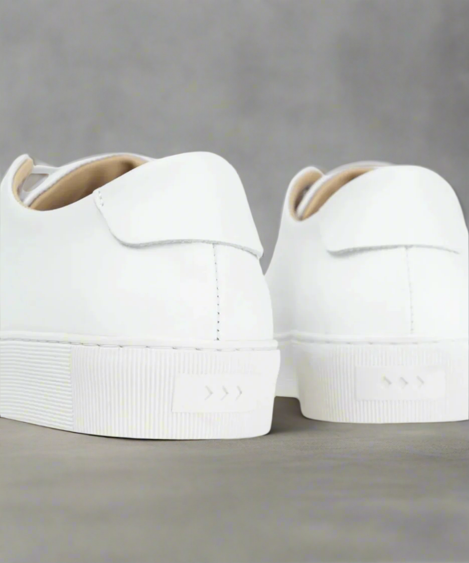 White minimalistic Royal RepubliQ sneakers on a gray background